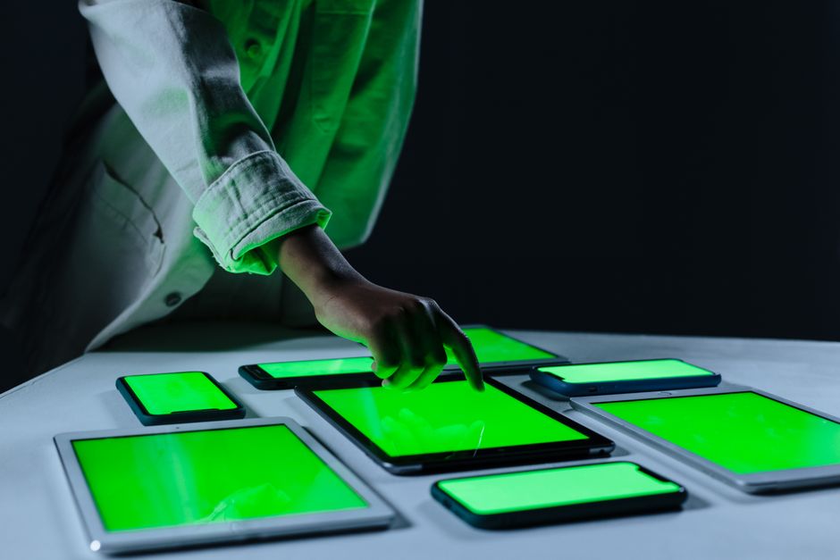 Ruka koja interagira s više digitalnih tableta na zelenom ekranu